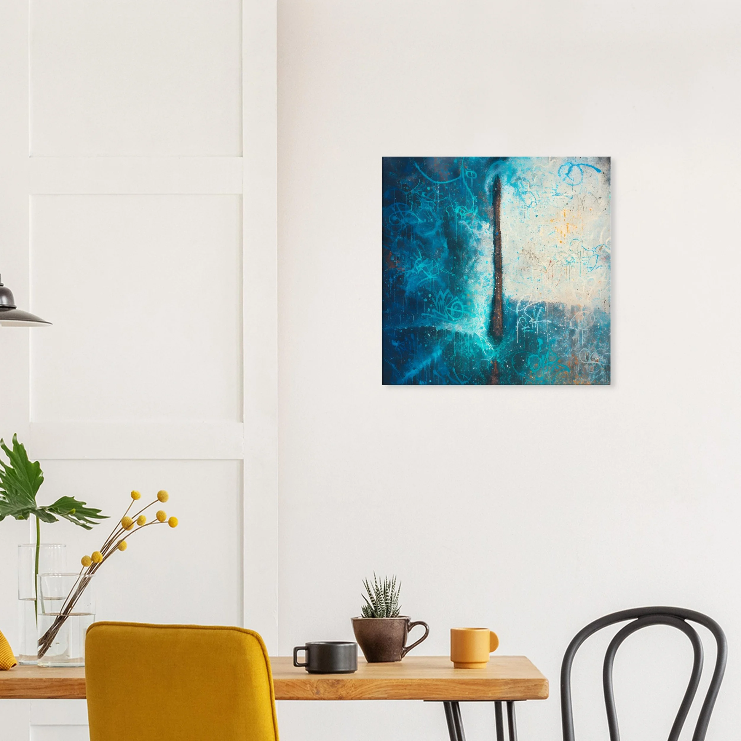 Interior of a room with a white wall, decorated with abstract blue artwork, a wooden dining table, a yellow chair, and various small plants and mugs.