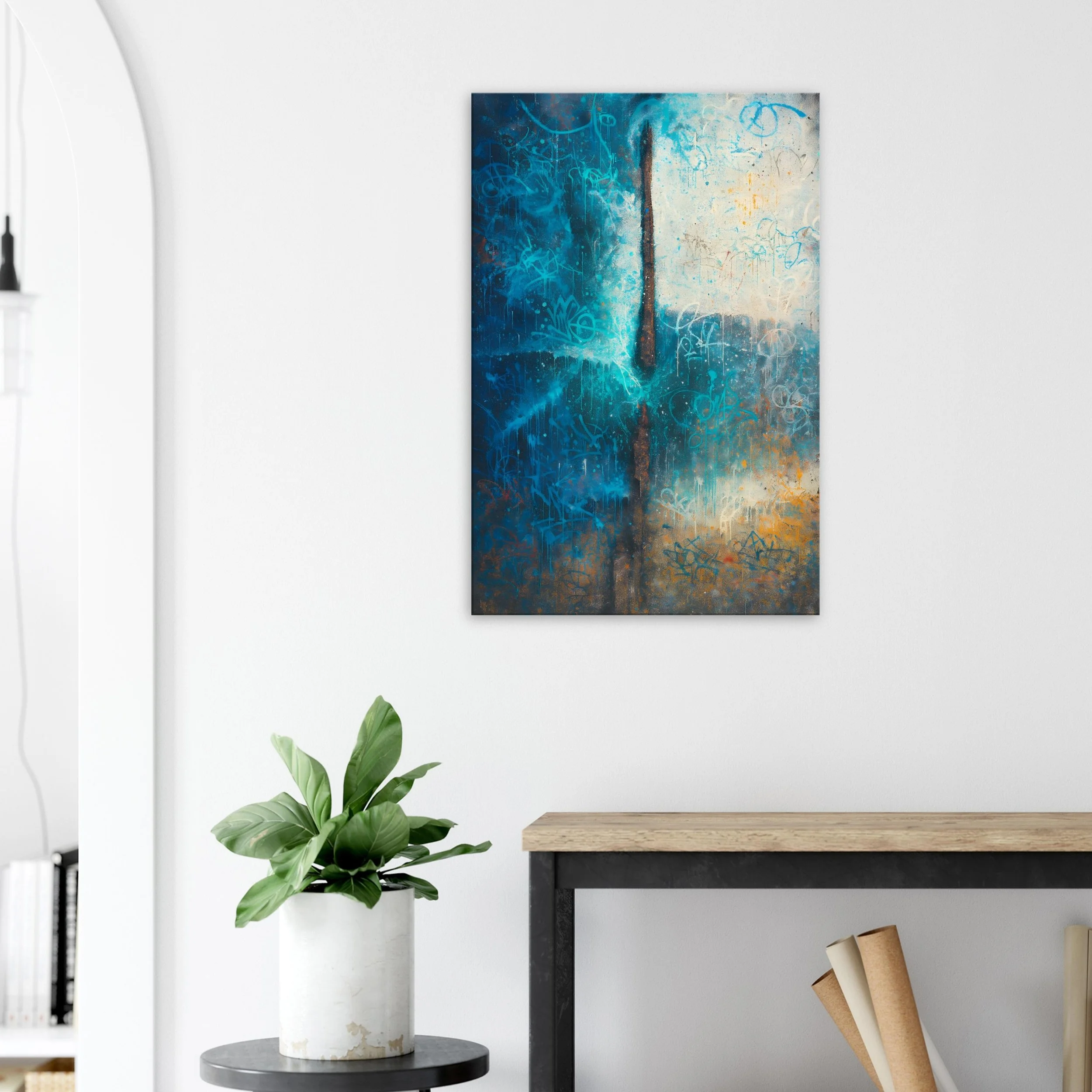 Abstract painting in shades of blue, white, and orange hanging on a white wall in a modern interior with potted green plant and a wooden and metal table.