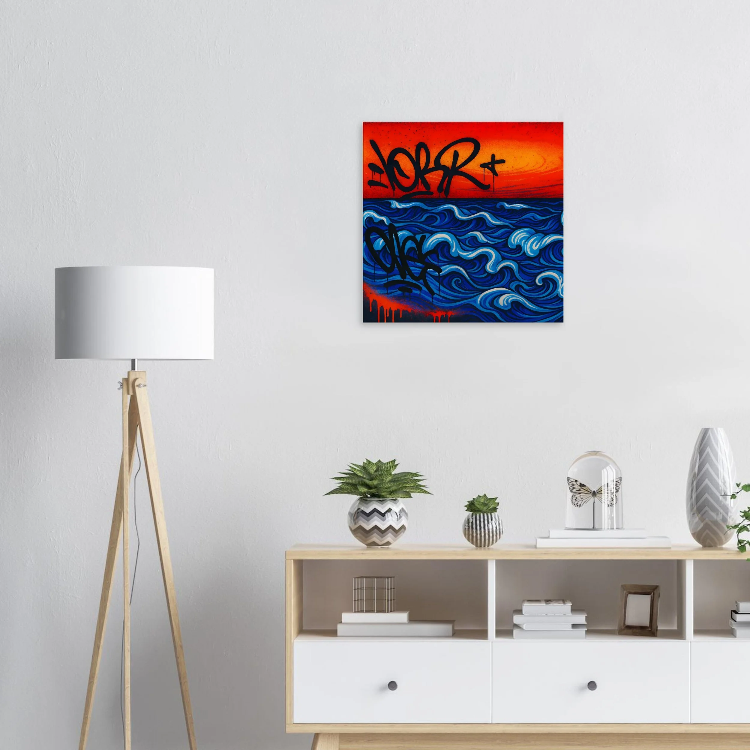 Modern living room wall with colorful abstract art featuring blue ocean waves and orange sunset, alongside a white sideboard decorated with potted plants, a decorative glass dome with butterfly, and a tall striped vase.