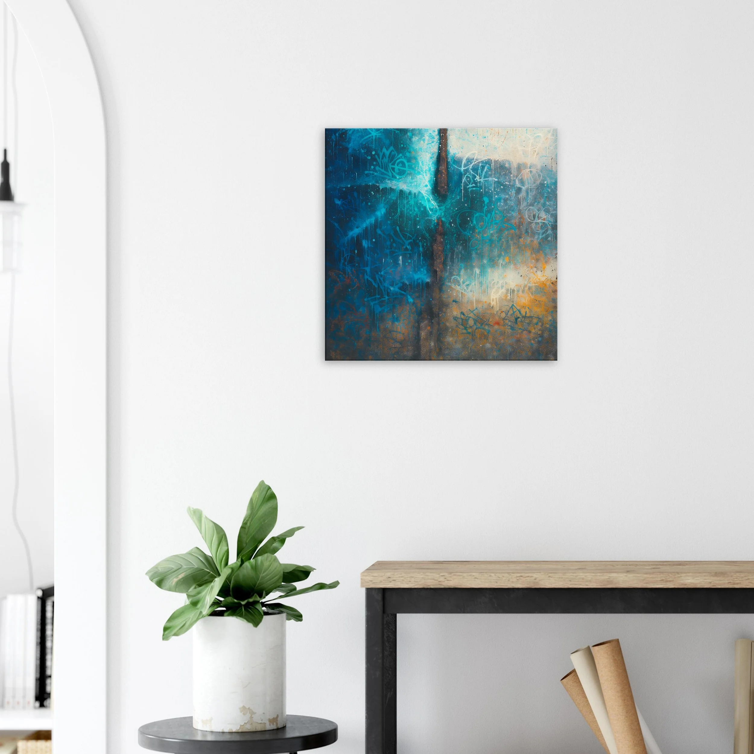 Abstract wall art with blue, brown, and beige tones hanging above a wooden table and green potted plant in a white pot in a home interior.
