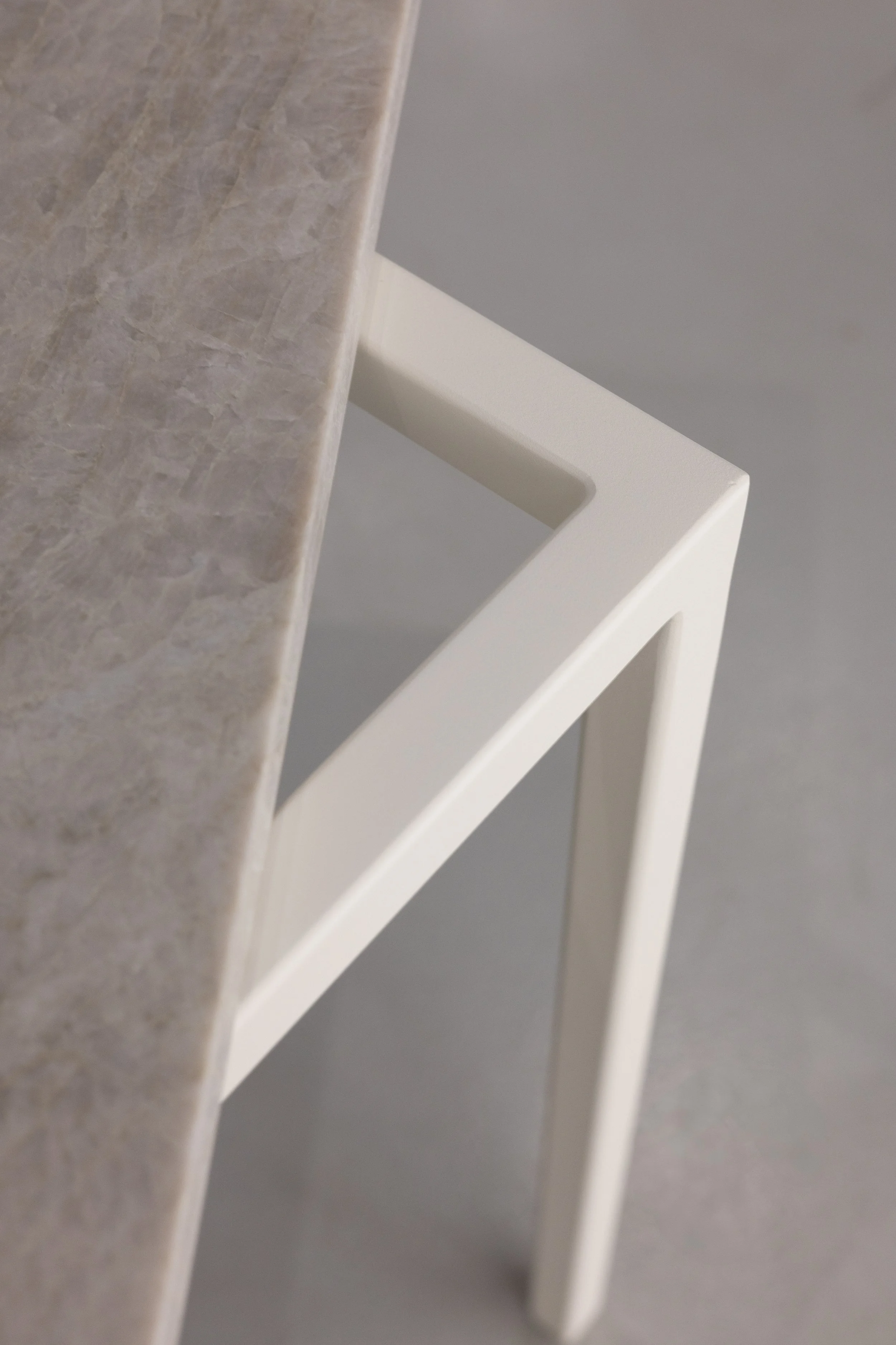 Close-up van een tafel met een marmeren blad en witte metalen frame.
