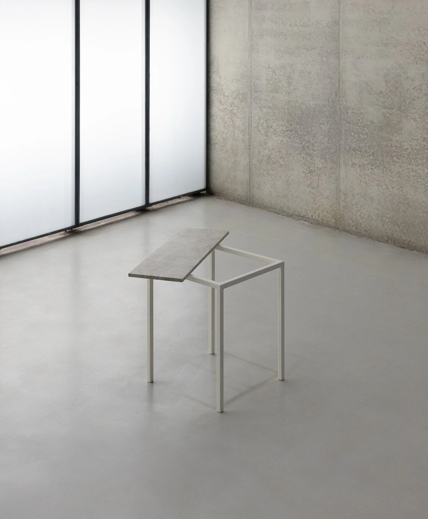Een minimalistish binnenruimte met een klein tafel met een houten blad en witte metalen poten, geplaatst op een grijze vloer, naast een grote glazen muur.