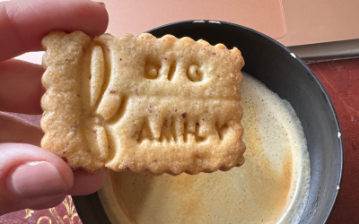 Gros plan / d'une main qui s'apprête à tremper son petit sablé Big Family dans son café