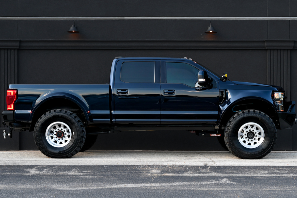 Black pickup truck parked in front of a black wall with two wall-mounted lights