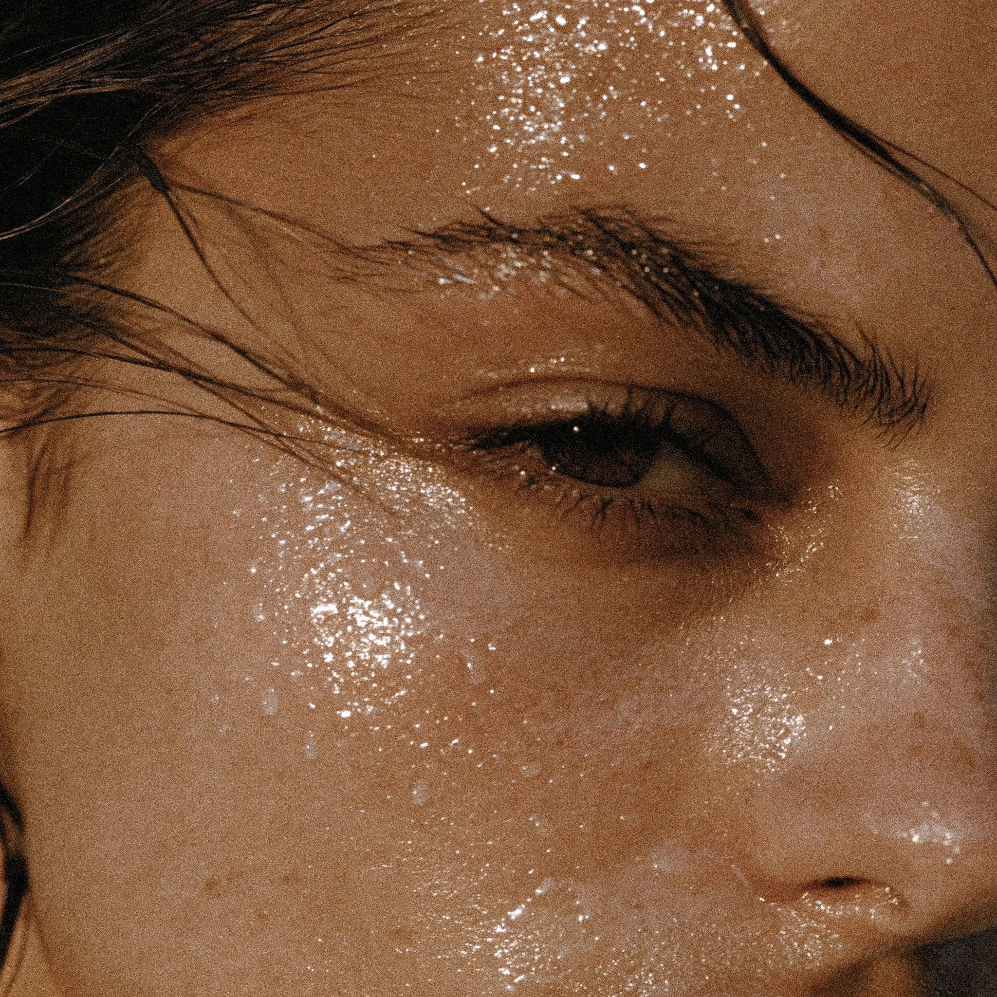 Close-up of a person's forehead with wet hair and shimmering glitter on the skin.