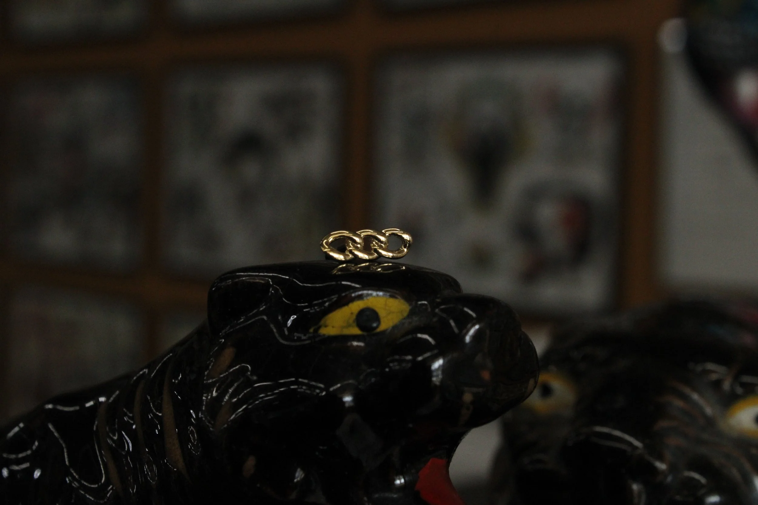 Close-up of a black ceramic tiger figurine with yellow eyes and a gold chain on its back.