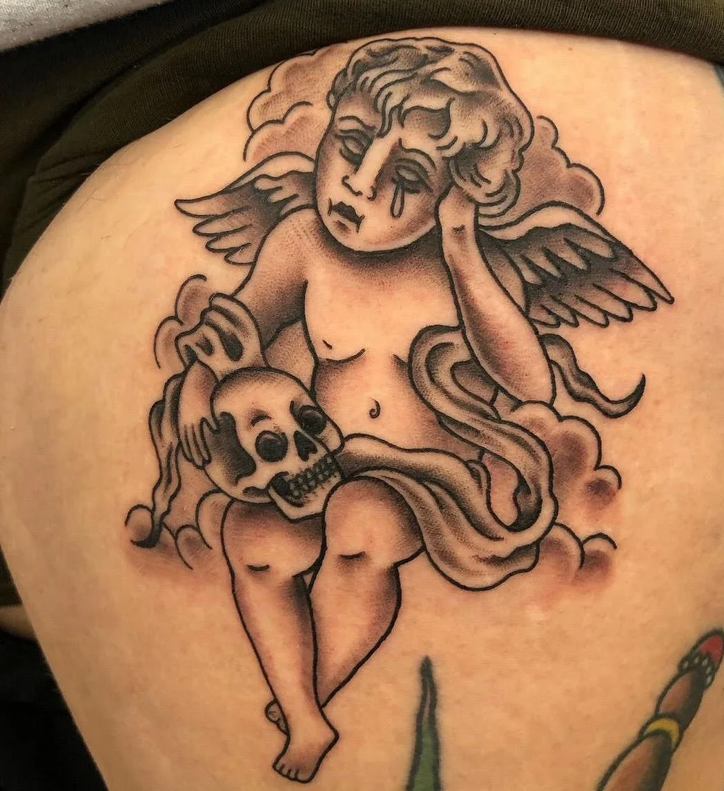 A sorrowful angelic figure holding a skull, done in classic black and grey. The soft shading and composition evoke a timeless sense of melancholy.