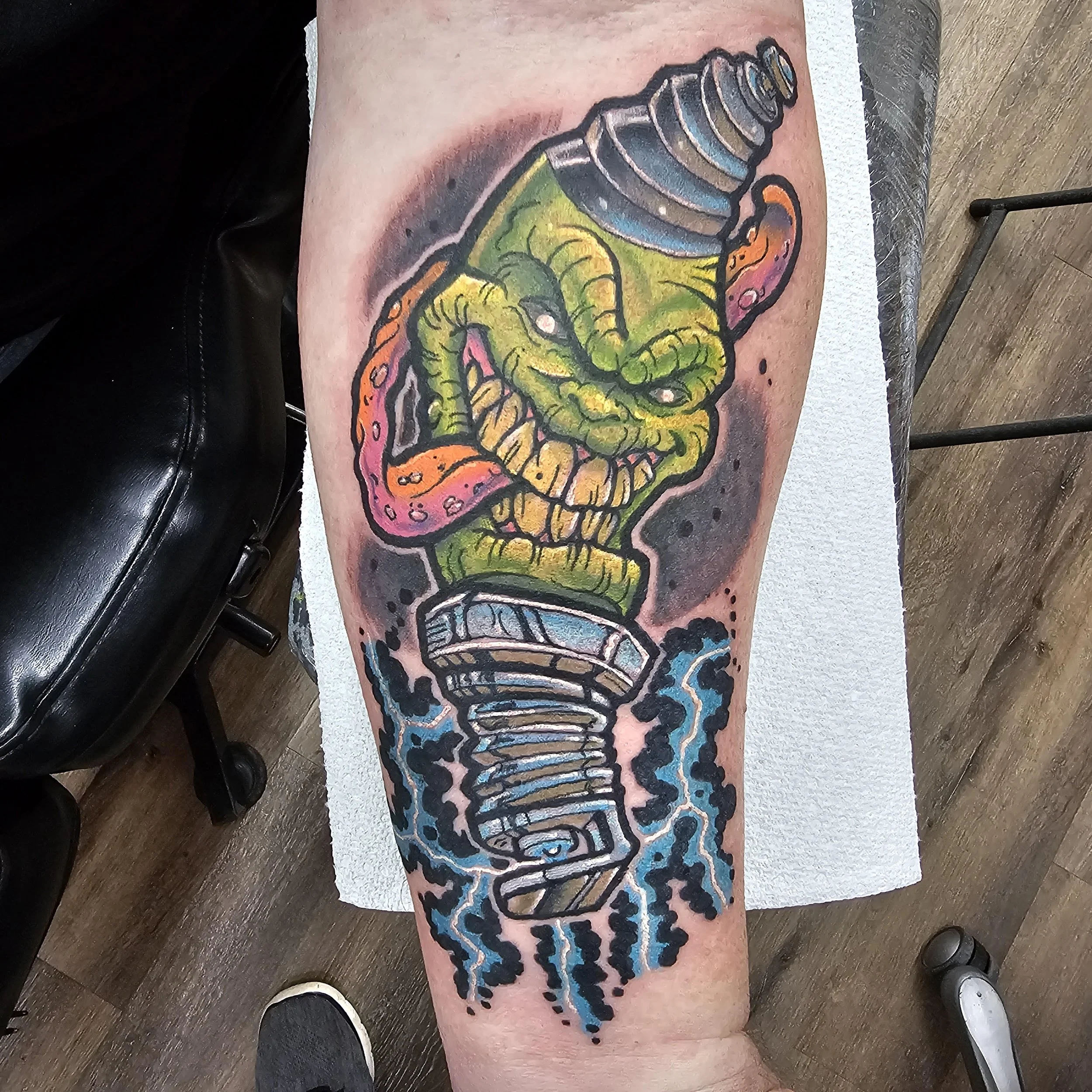 A mischievous green creature with bulging eyes and a twisted grin emerges from a spark plug surrounded by bursts of electric energy. The character design, bold colors, and comic-book exaggeration make it a high-impact, fun illustrative piece.