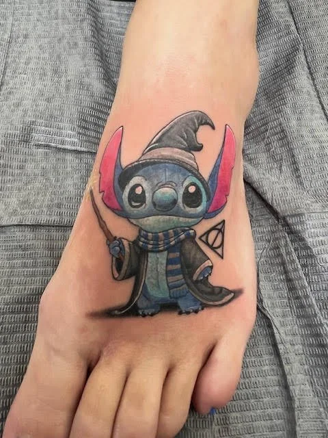 A charming tattoo of Stitch dressed as a wizard, complete with a wand and scarf. The pastel palette and fine detail bring together elements of fantasy and beloved animation.