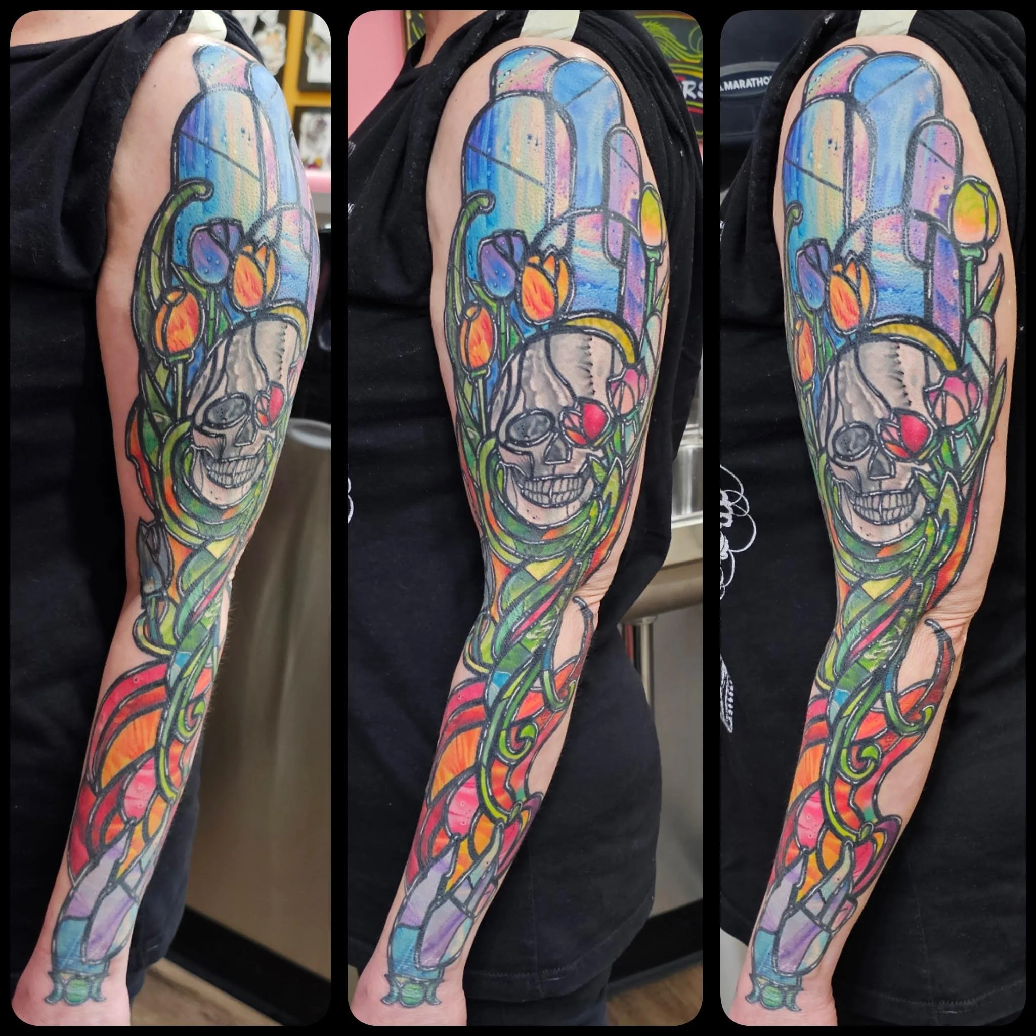 A vibrant stained-glass inspired sleeve combines flowing vines, bold floral shapes, and a stylized skull framed by cathedral-like windows. The saturated colors, heavy black linework, and organic curves create a luminous, illustrative look with strong