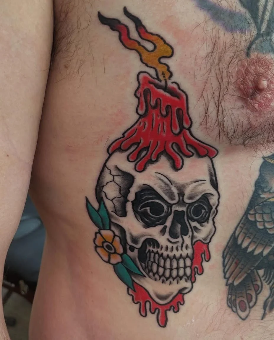 A dramatic skull topped with dripping red wax and a burning flame. The contrast between black shading and vivid color accents gives this tattoo a haunting yet balanced feel.