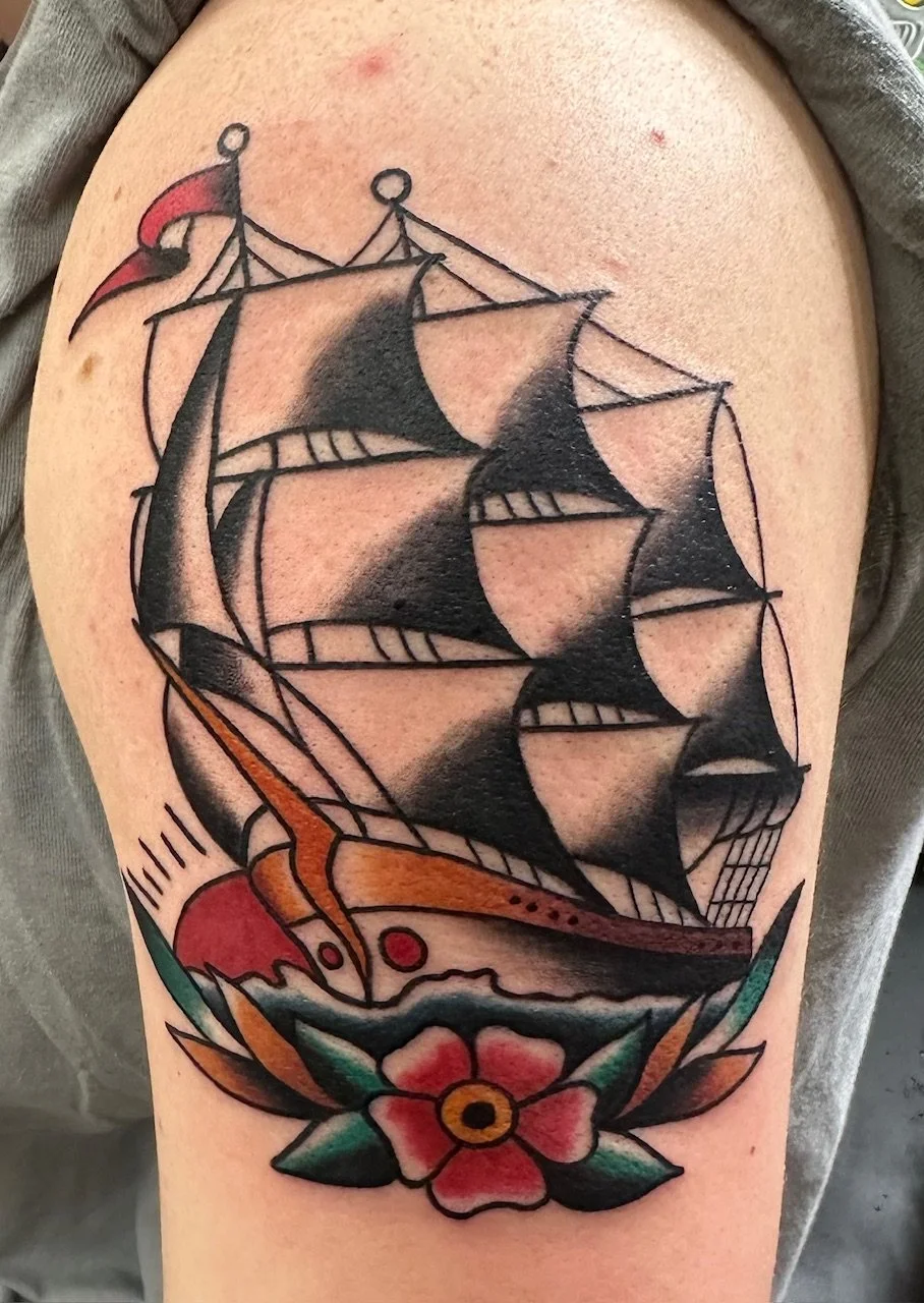 This classic sailing ship tattoo embodies the spirit of old-school tattooing, with bold black shading and striking red and green accents. The design captures a sense of adventure and nostalgia through its strong, traditional composition.