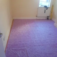 Carpet installation in progress including fitting and trimming in accordance with housing standards.