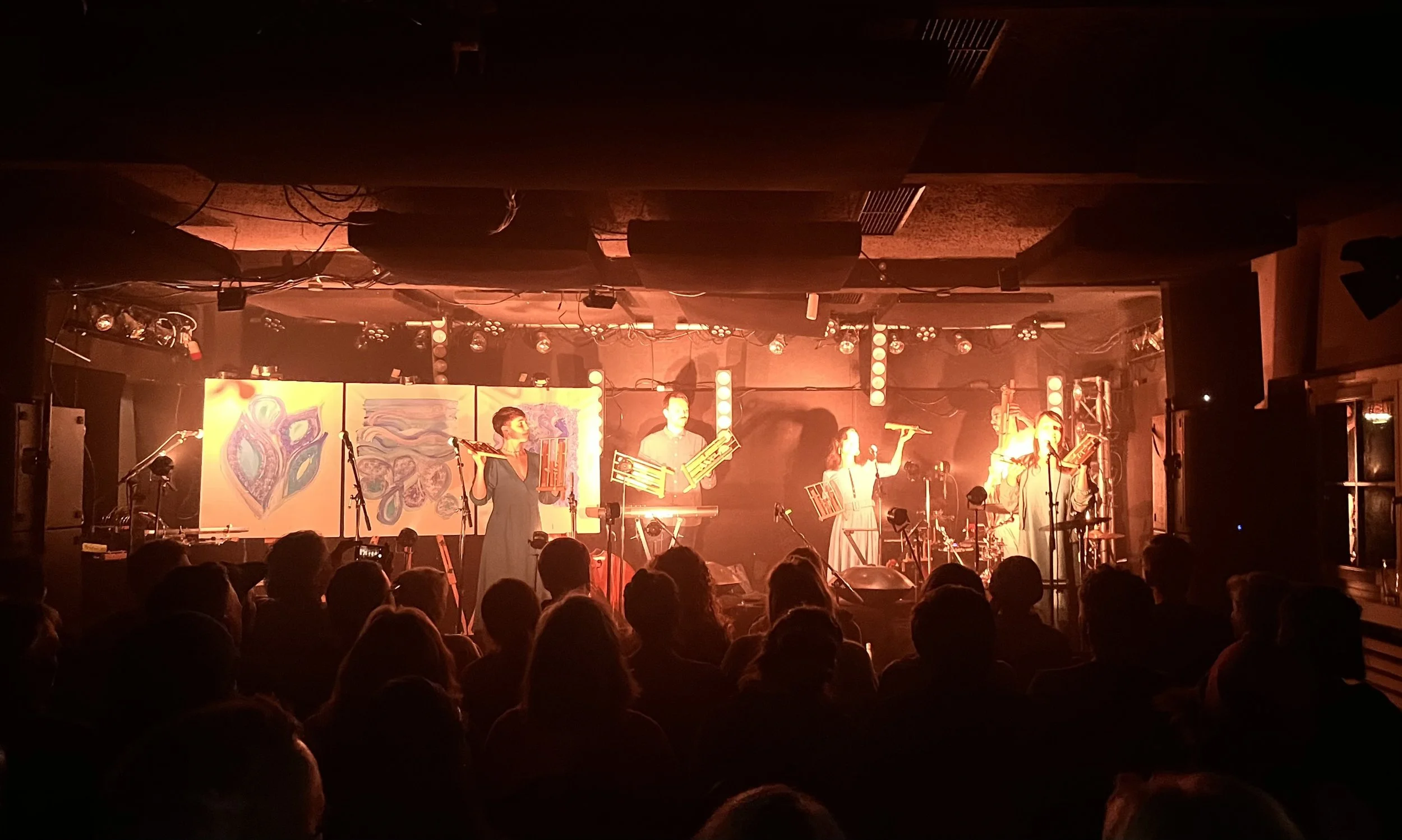 Eine Live-Musikperformance in einem dunklen Veranstaltungsraum mit mehreren Musikern auf der Bühne, im Freiraum Übersee