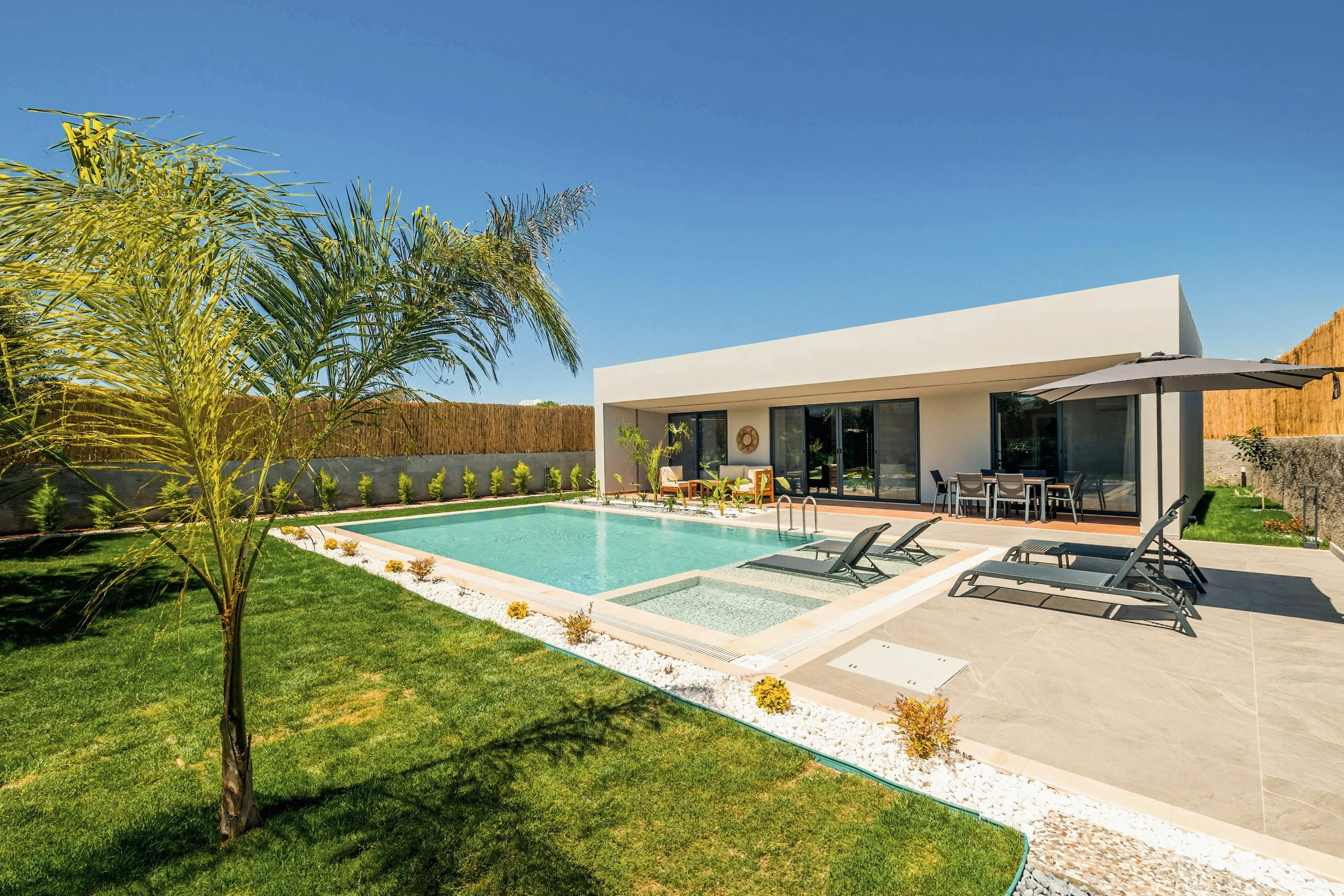 Modern house with private swimming pool, outdoor lounge chairs, and patio area on sunny day