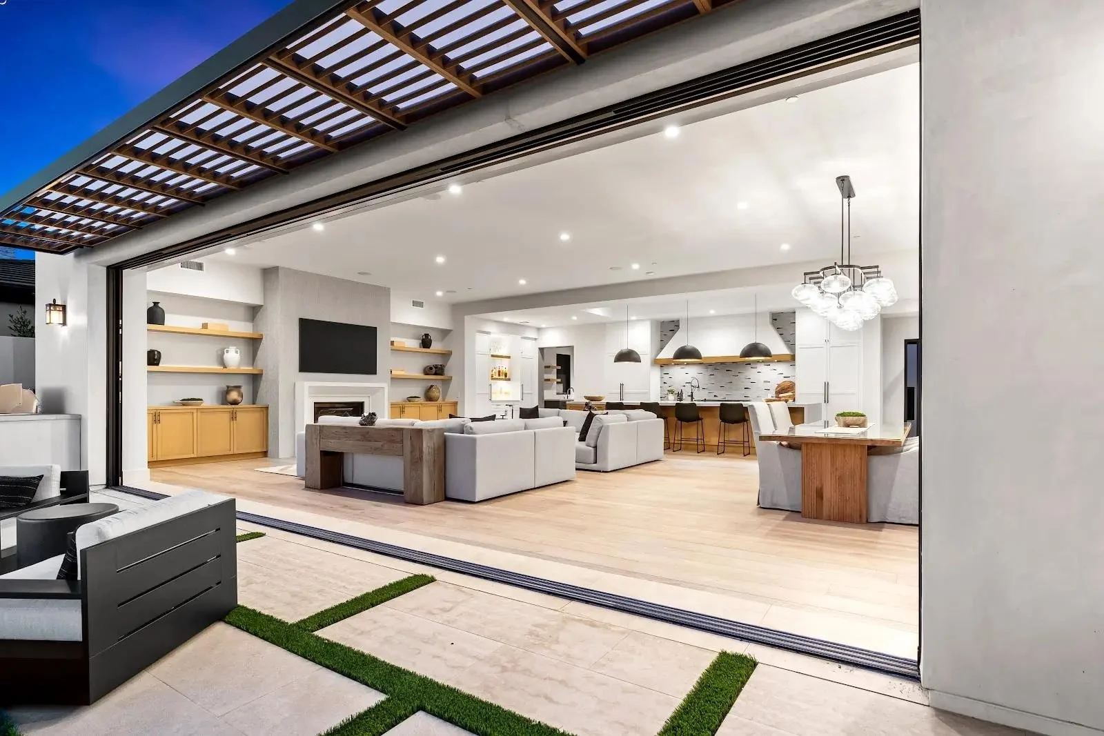 Open-concept living room and kitchen with sliding glass doors, modern furniture, and minimalist decor.