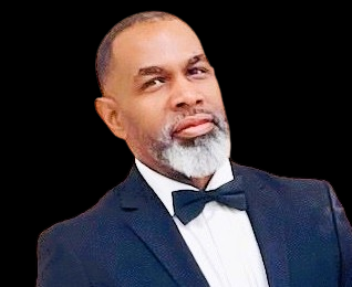 A man with a serious expression, wearing a navy blue tuxedo and bow tie, with a gray beard and balding head.