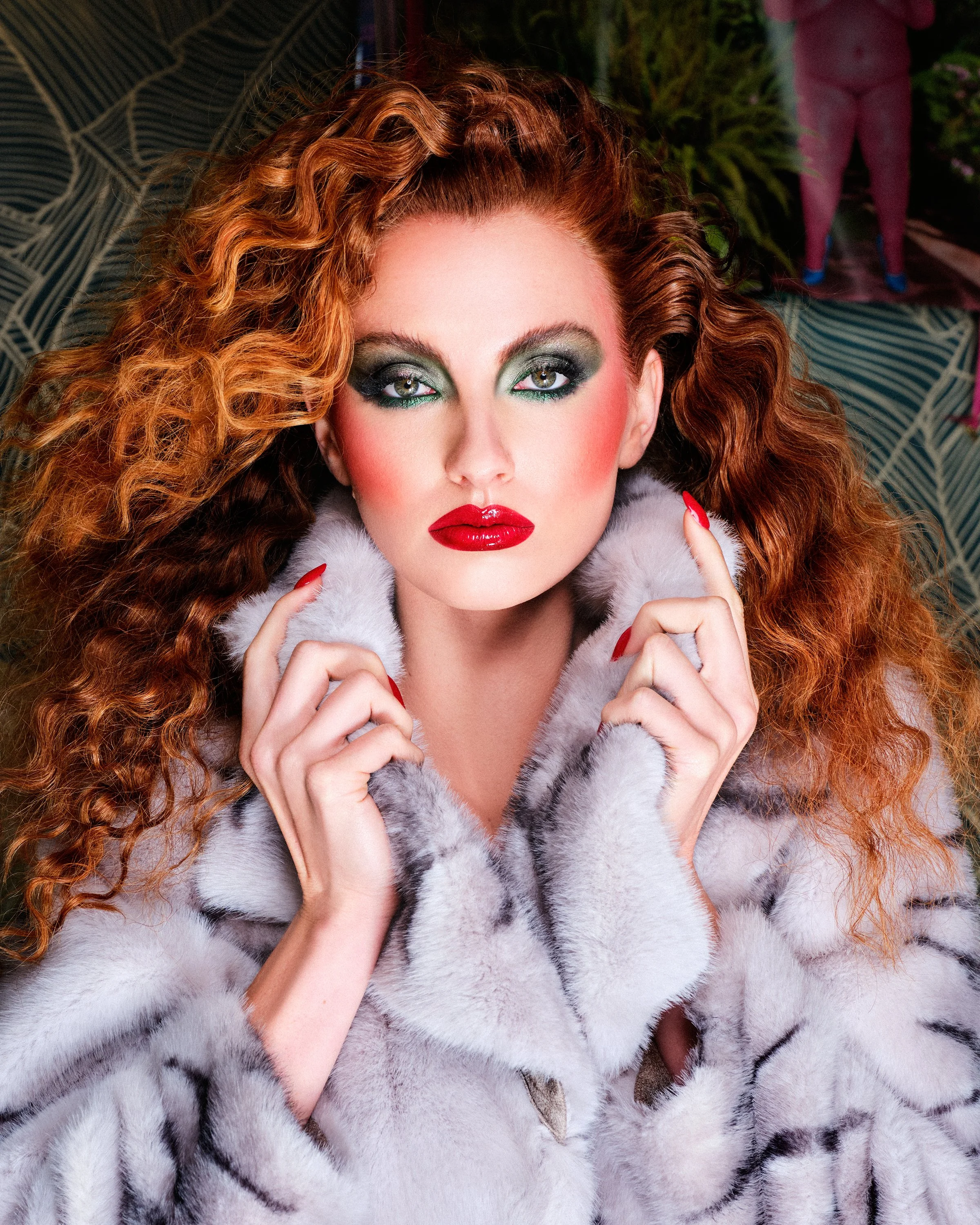 A woman with curly red hair and vibrant makeup, wearing a white fur coat with black markings, holding the coat with her fingers.