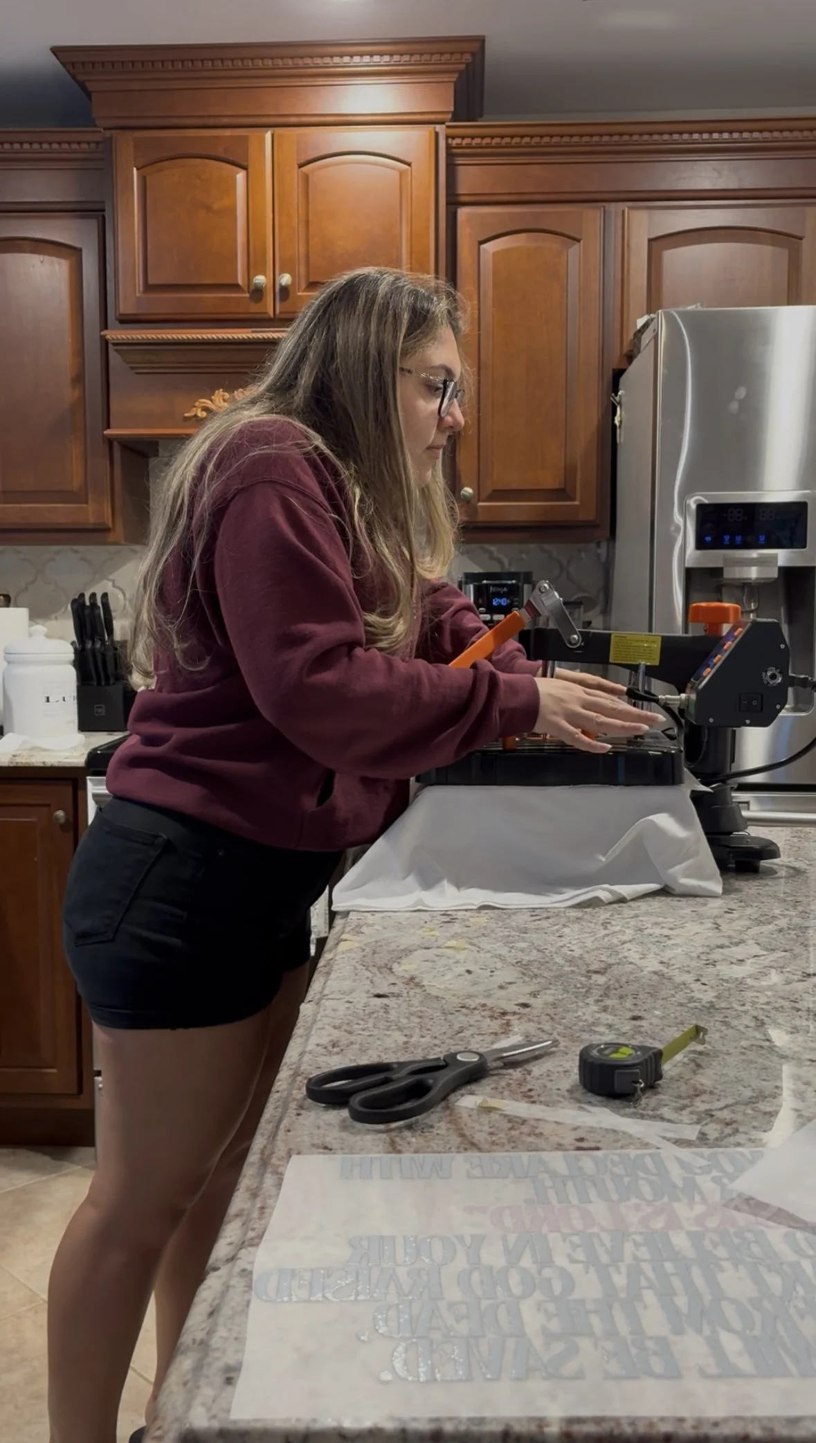 A woman operating a heat press machine, making scripture inspired Christian t-shirts