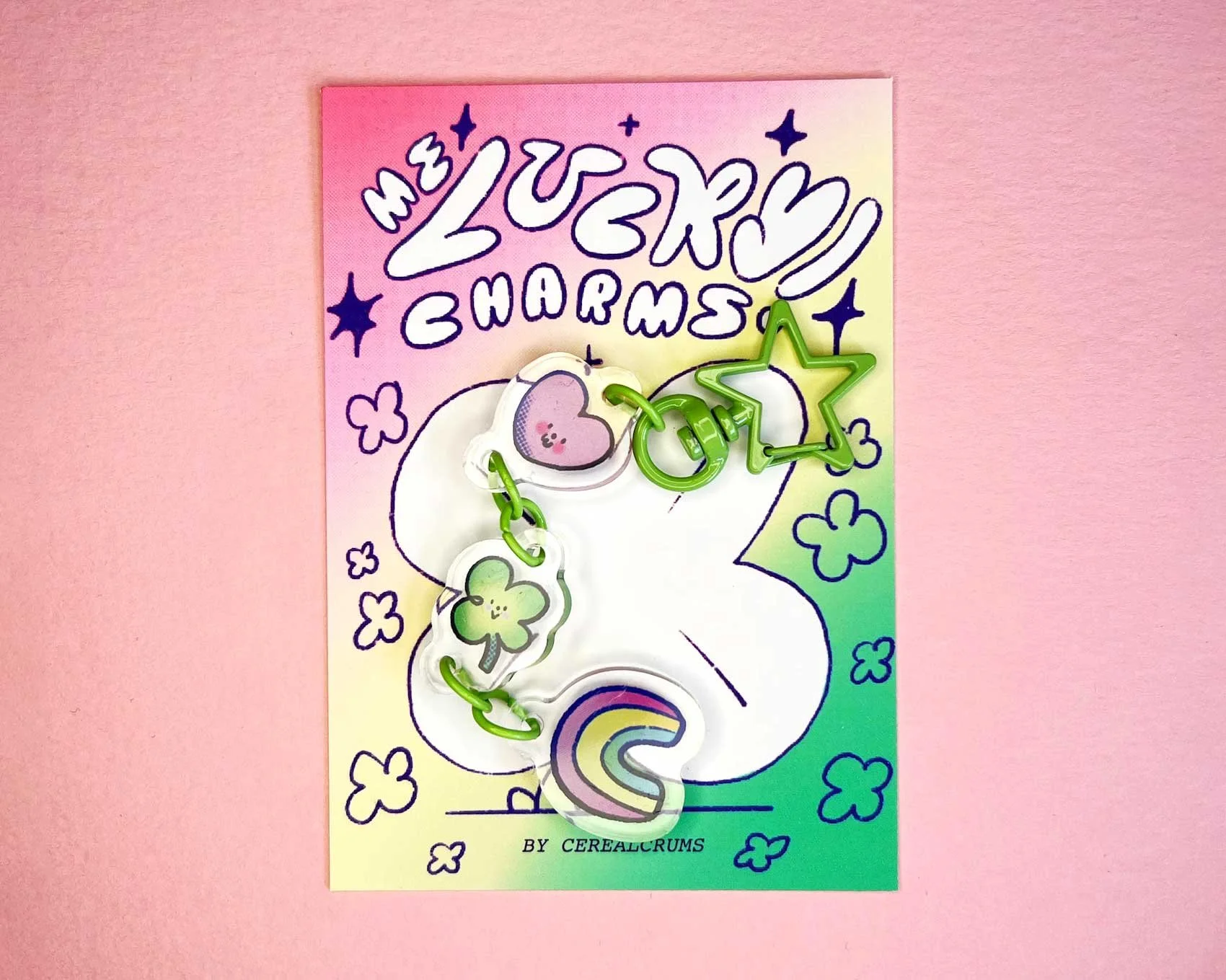 Lucky Charms keychain illustrated gift. Pink and green four leaf clover, hearts and rainbows on a green star shaped keychain.