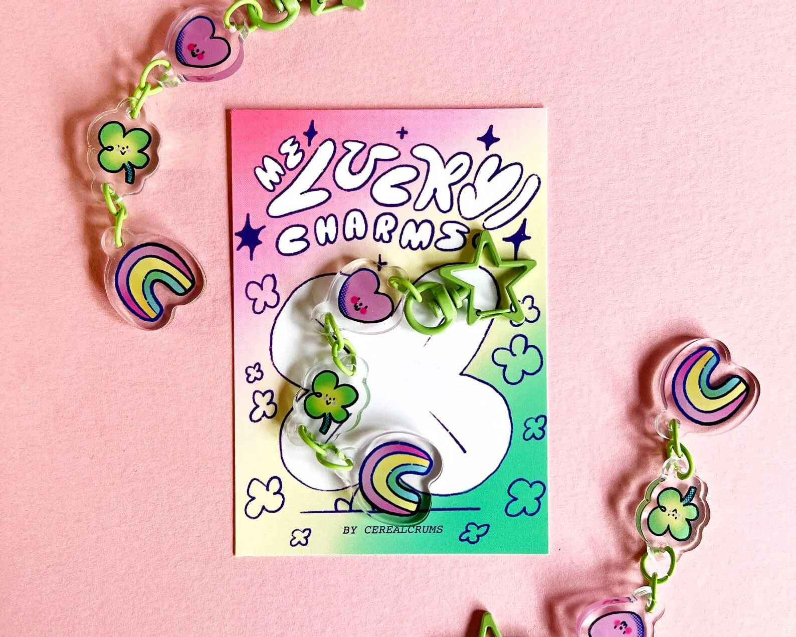 Lucky Charms keychain illustrated gift. Pink and green four leaf clover, hearts and rainbows on a green star shaped keychain.