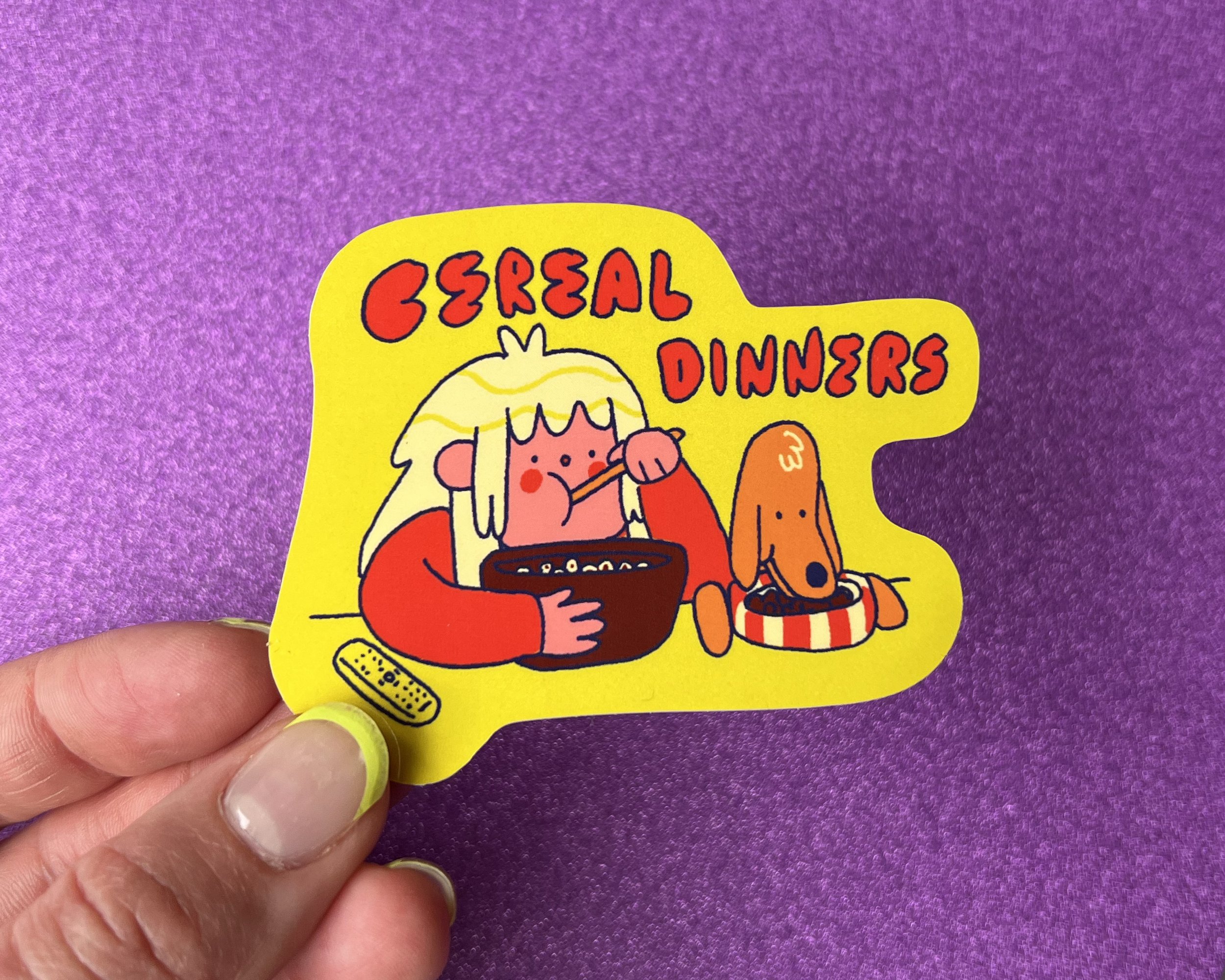 A colorful sticker with a cartoon girl and dog eating cereal, with the words "Cereal Dinners" written above.