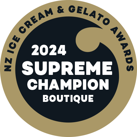 A circular badge for the 2024 NZ Ice Cream & Gelato Awards with a beige outer ring, black inner circle, and a gold scoop icon at the top, displaying the text '2024 SUPREME CHAMPION BOUTIQUE' in bold white letters.