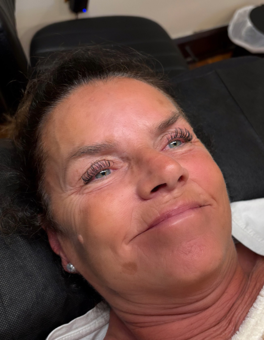 Four close-up photos of a young woman with light skin, wavy blonde hair, and makeup, lying on a black leather surface, with different facial expressions and angles.