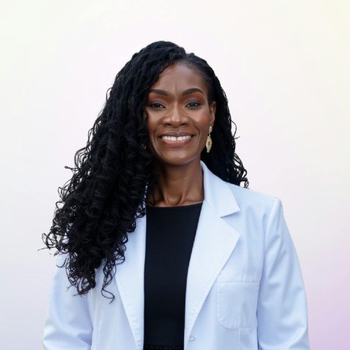 Smiling woman with long curly black hair, wearing a white lab coat over a black top, against a plain white background.