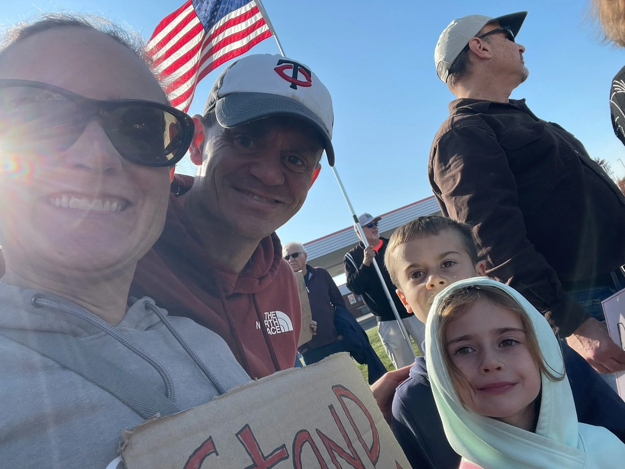 Christos's family gathered outdoors participating in a No Kings protest.