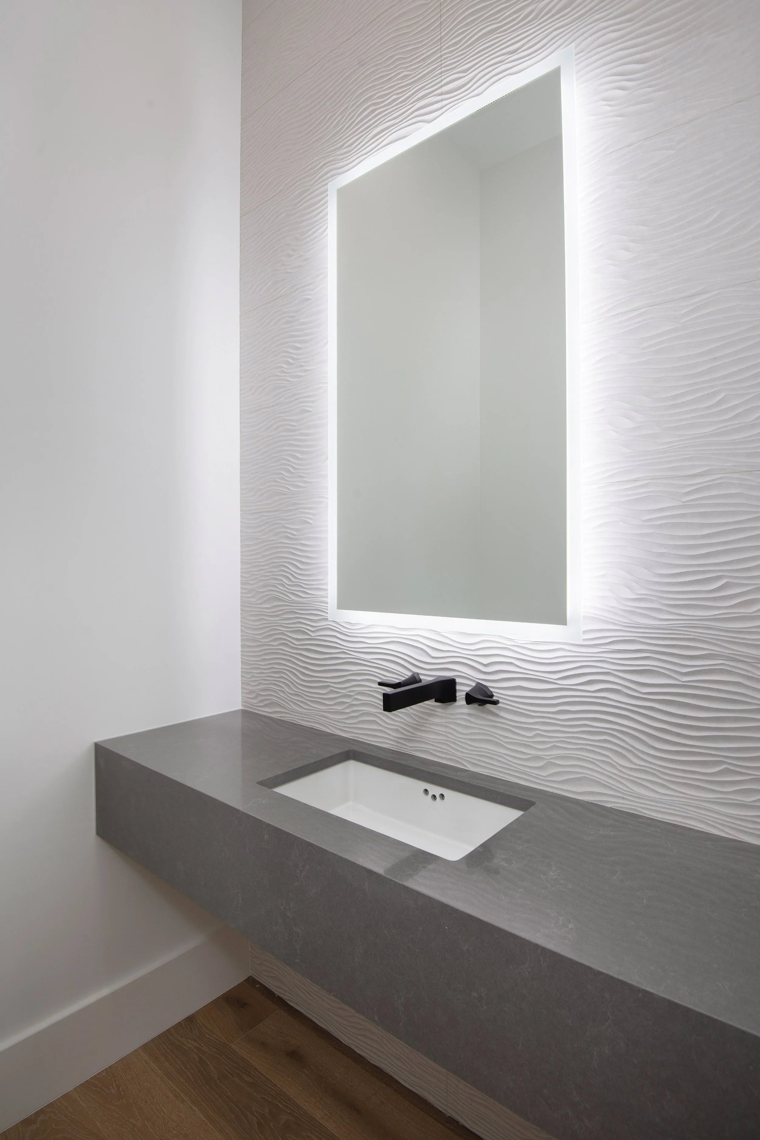 Modern bathroom vanity with a rectangular mirror, black faucet, and gray countertop with a built-in sink.