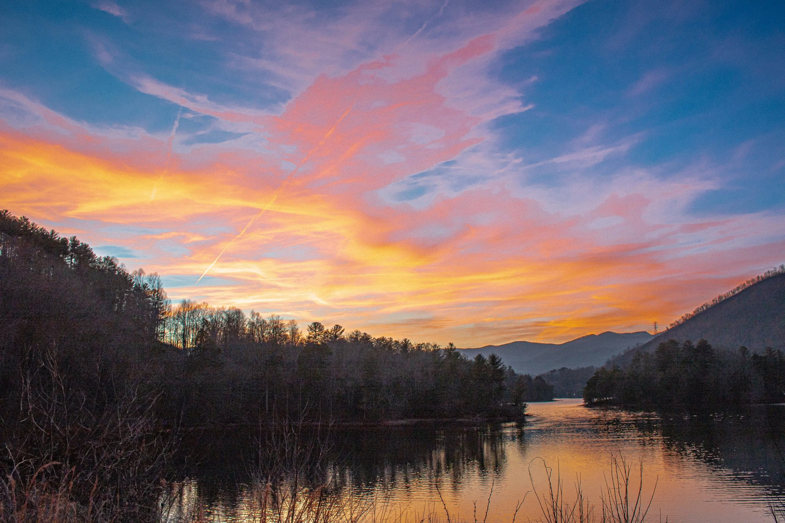 Colorful sunset over a river with mountains and trees in the background