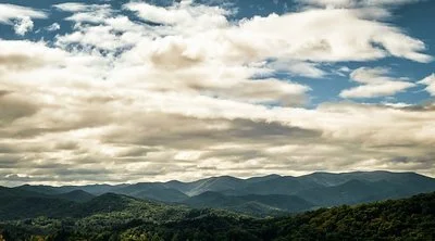 Landscape of rolling hills and mountains beneath a partly cloudy sky.