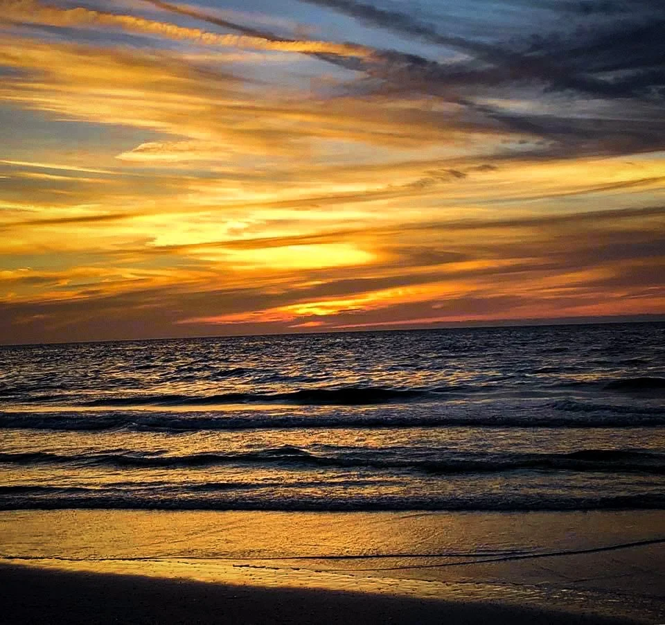 Sunset over the ocean with colorful clouds and reflected light on the water.