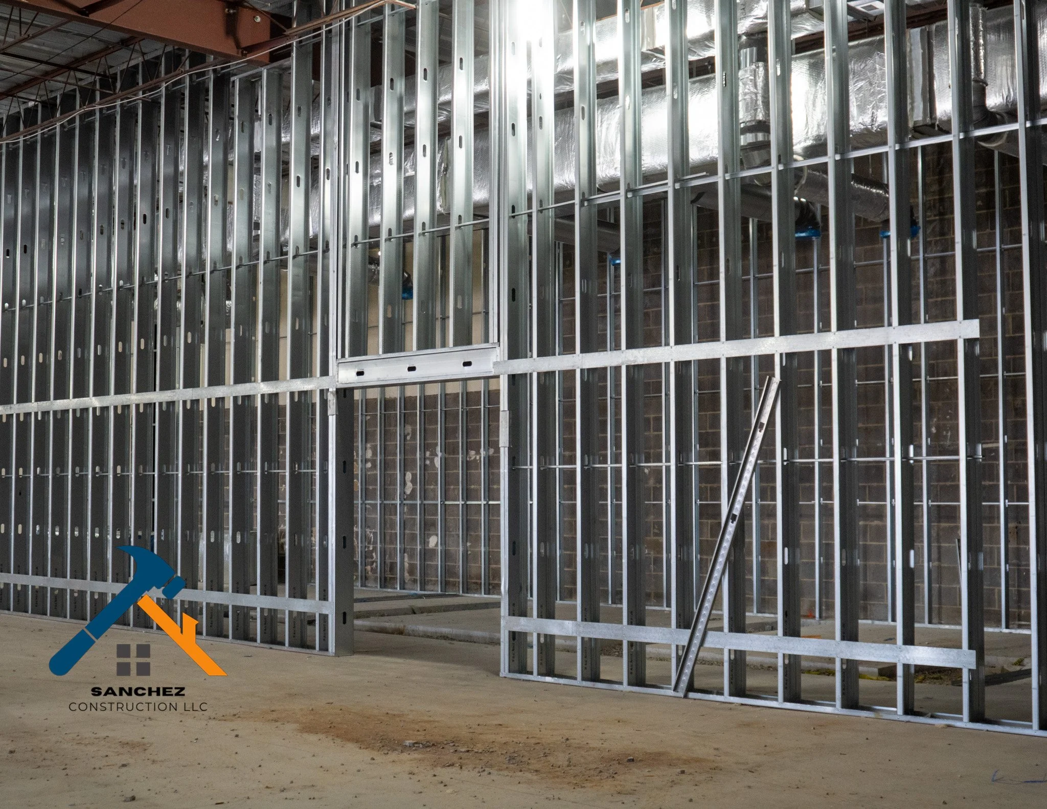 Steel framing construction for a building Interior with visible metal studs, insulation, and wiring in progress.