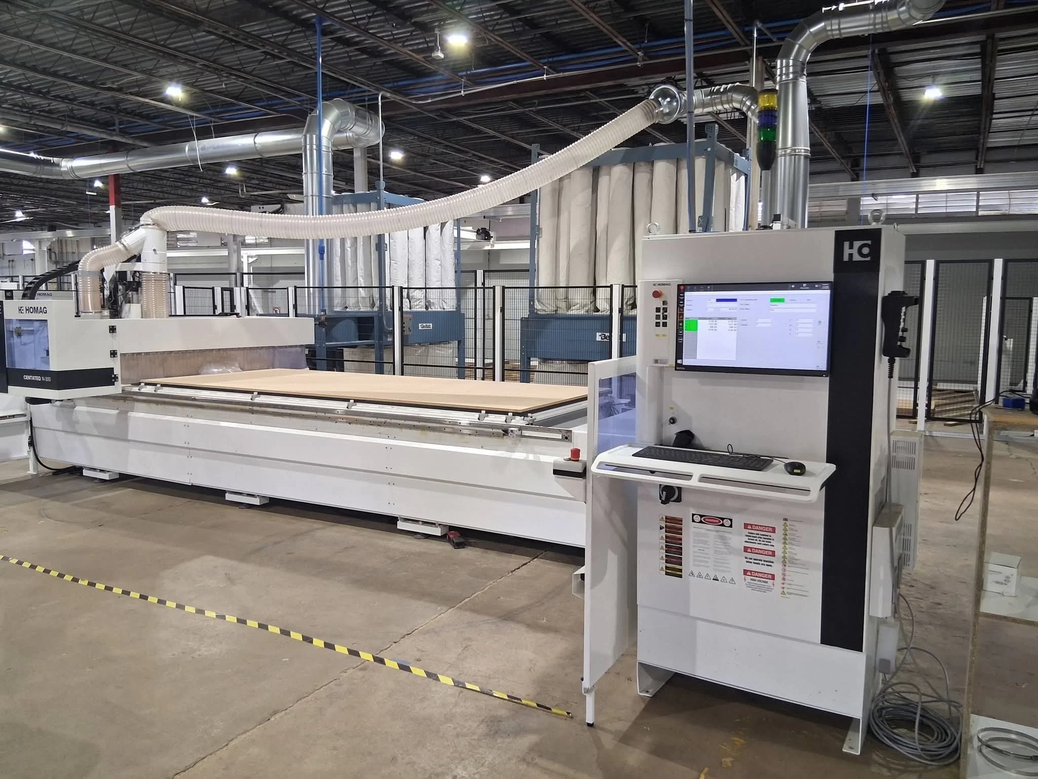 Large CNC machine in an industrial setting with a computer control station on the right.