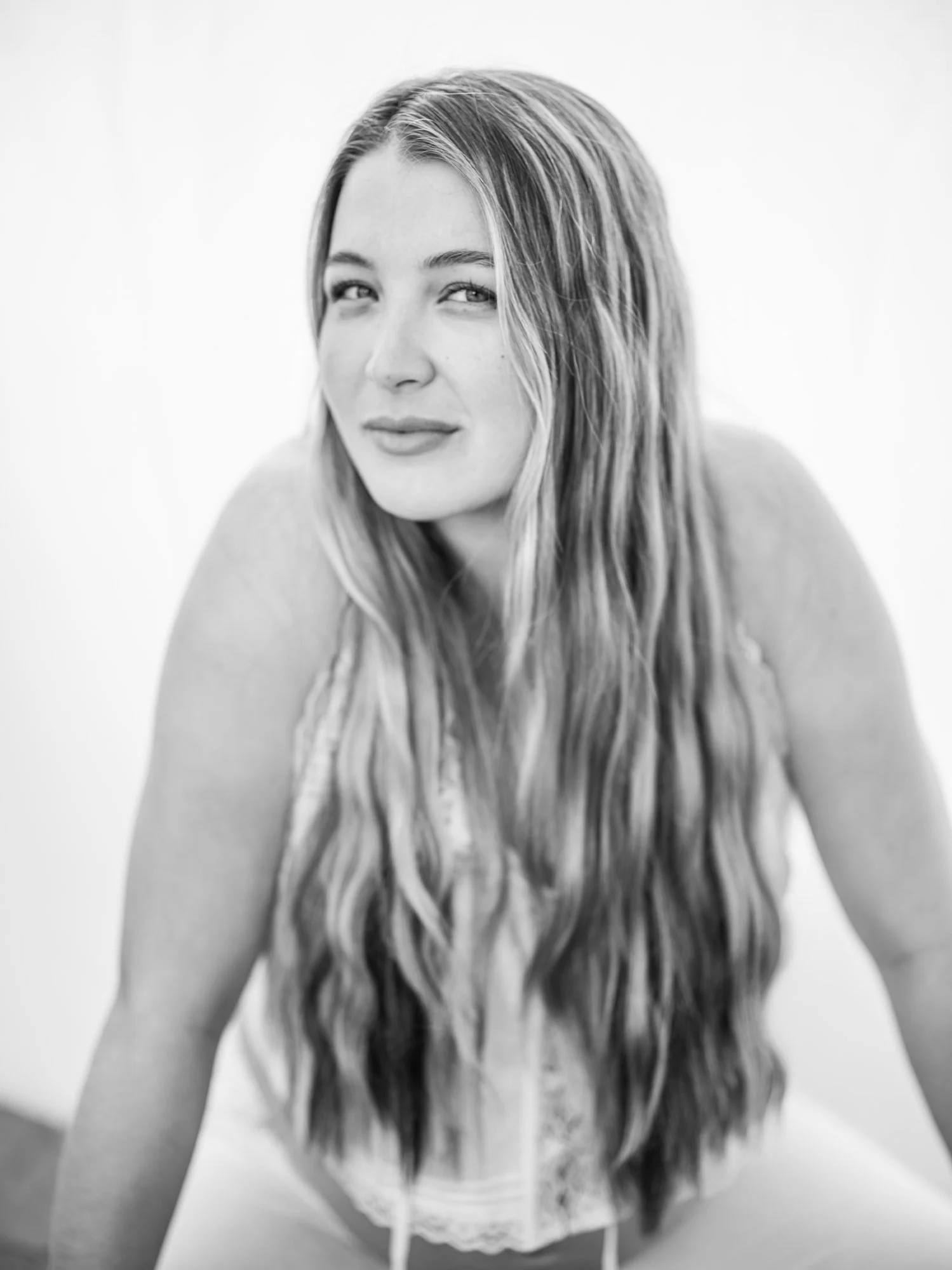 Black and white portrait of a woman with long, wavy hair, looking at the camera with a slight smile.