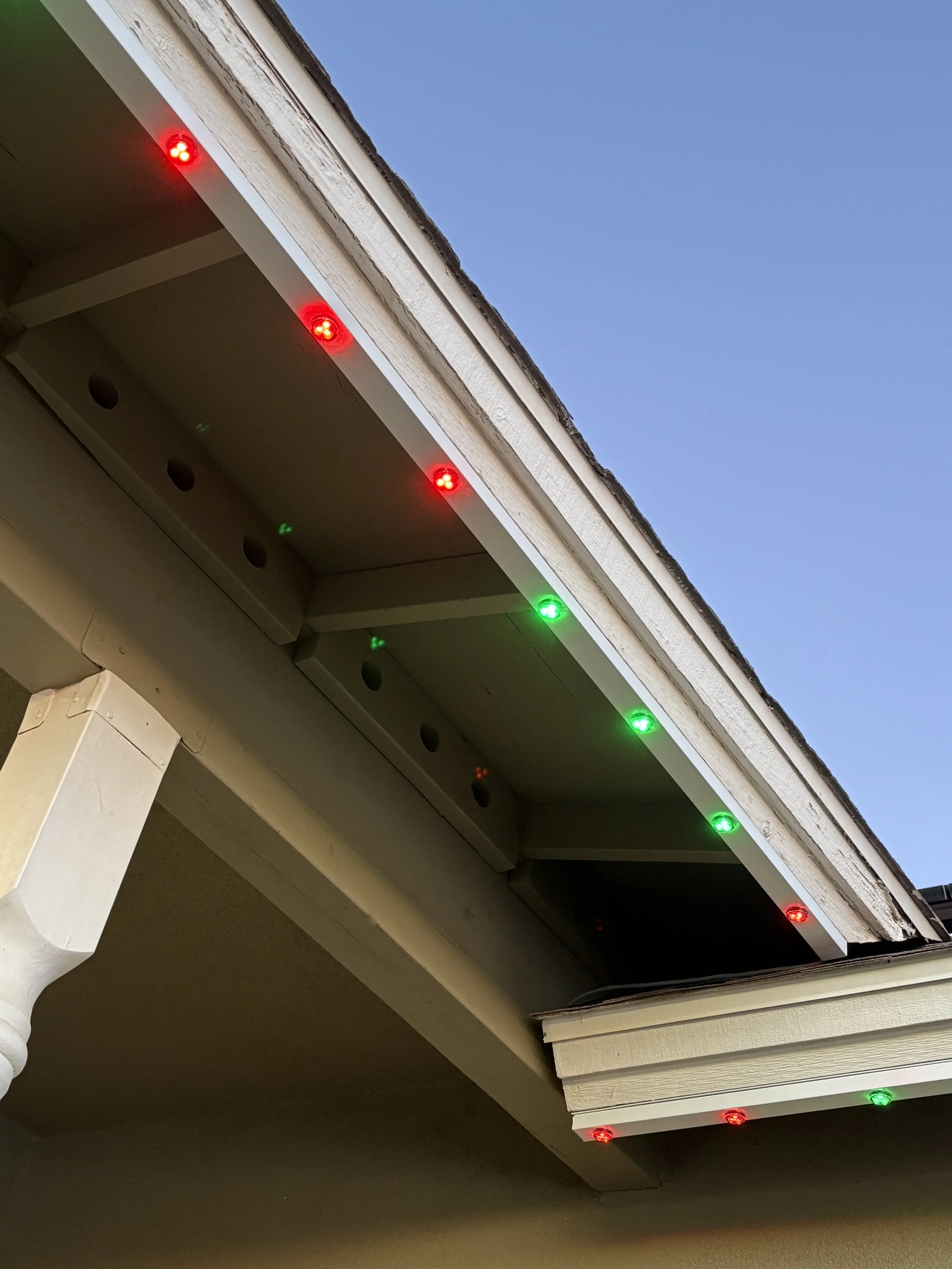 White permanent track lighting hiding all screws and hardware highlighting Christmas colored lights in Queen Creek