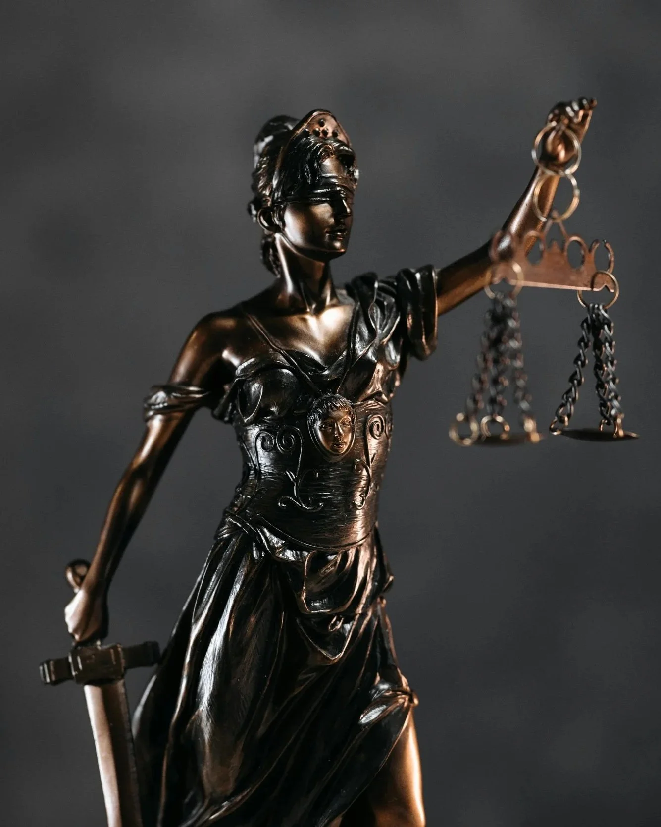 Bronze statue of Lady Justice holding scales in her left hand and a sword in her right hand, with her eyes covered.