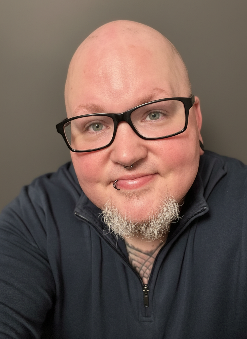 A person with a shaved head, glasses, and a goatee.