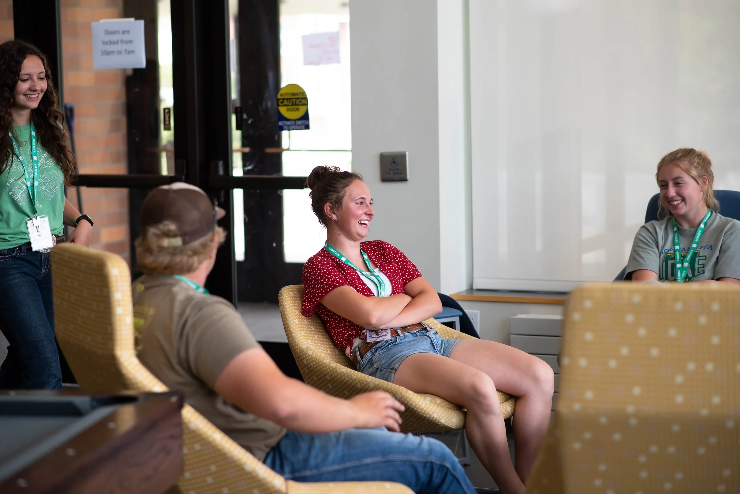 Group of young women engaging in a lively conversation in a casual indoor setting, smiling and laughing.