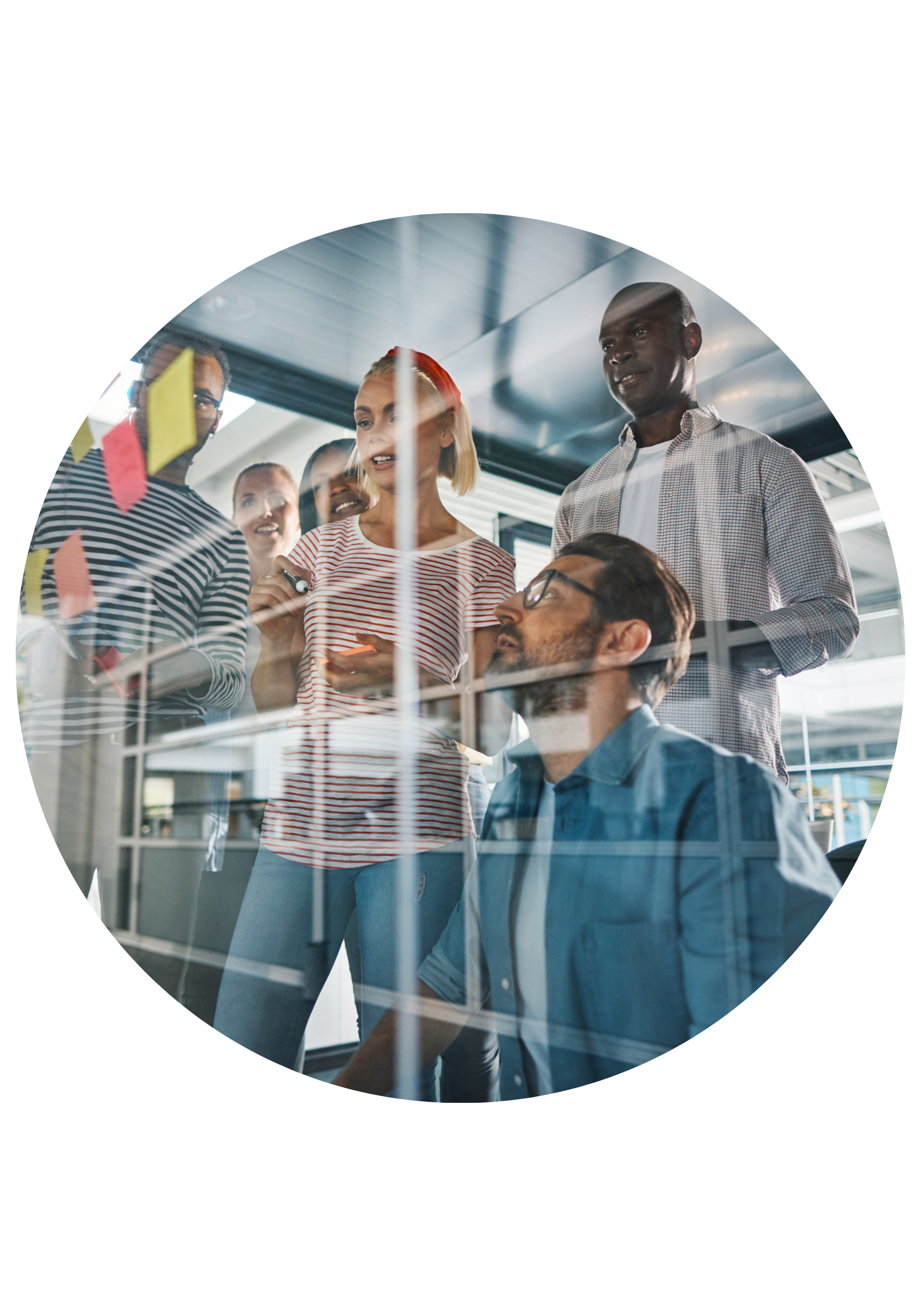 A diverse group of six people gathered around a glass wall with sticky notes, collaborating and discussing ideas in a modern office.