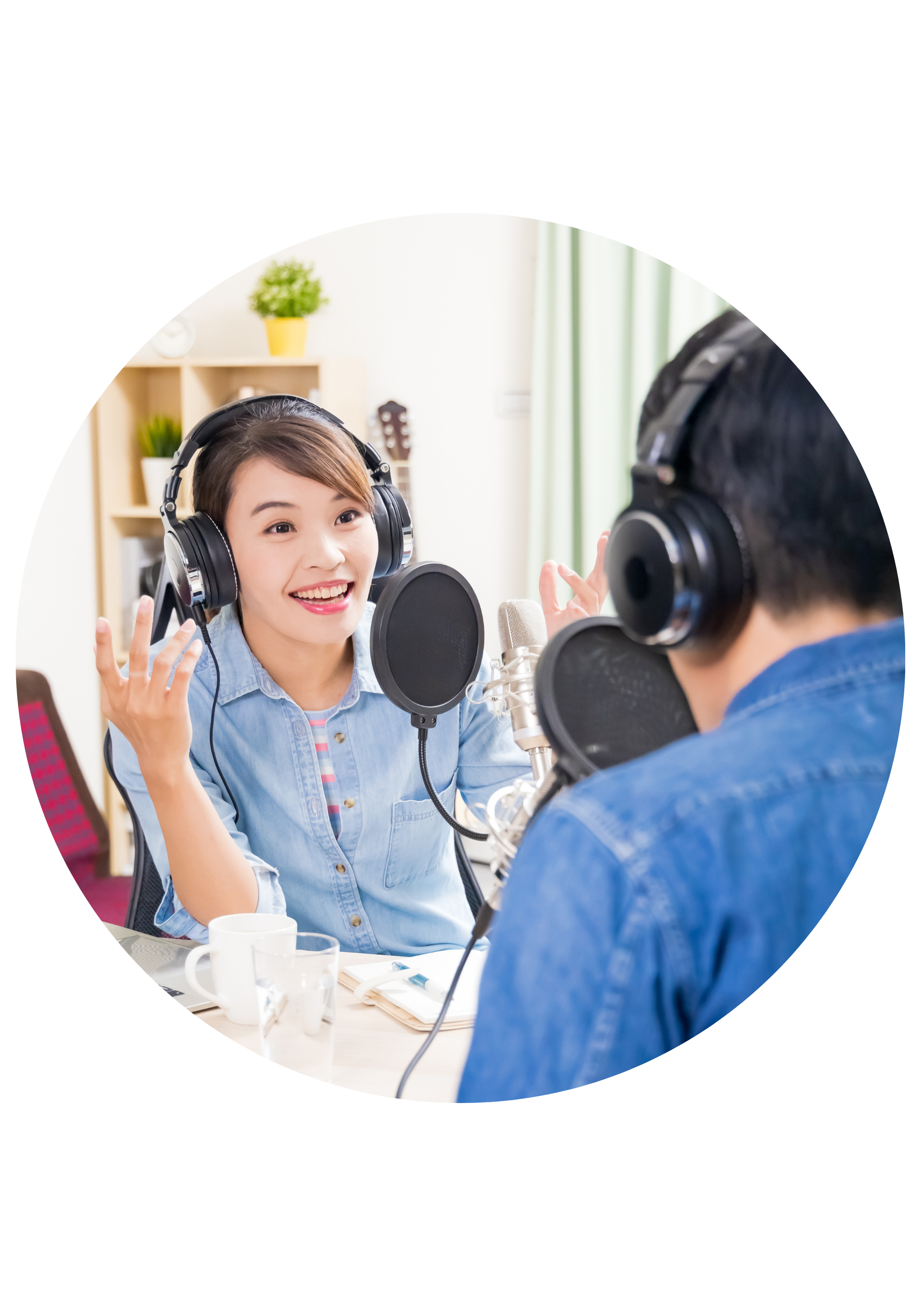 A woman and a man recording a podcast with microphones in a studio.
