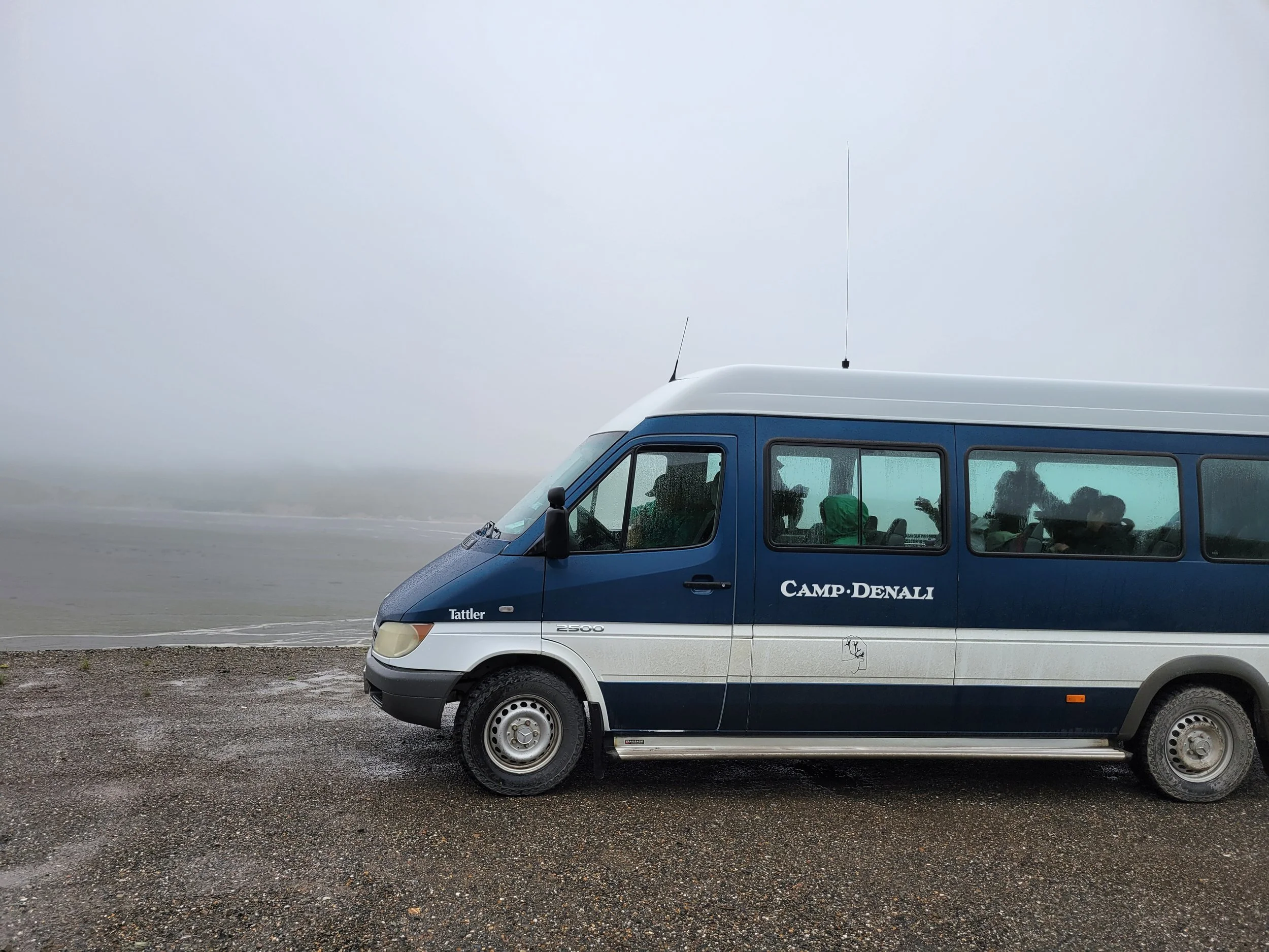 Camp Denali naturalist van parked along a foggy gravel road during rainy weather in Denali National Park.