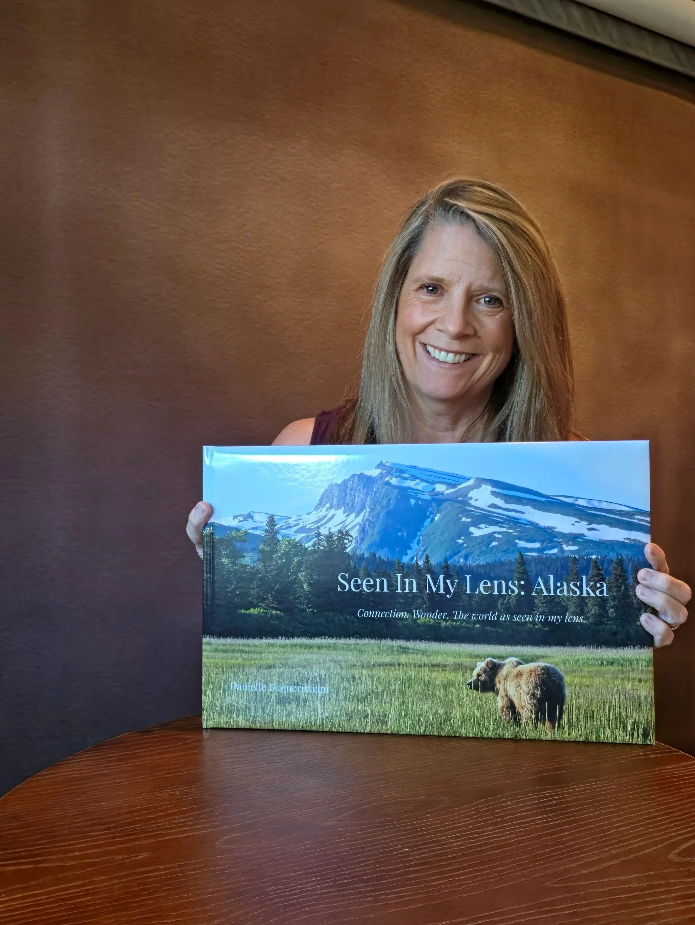 “Woman holding a large printed Alaska photography book, representing final test version of coffee table book project”