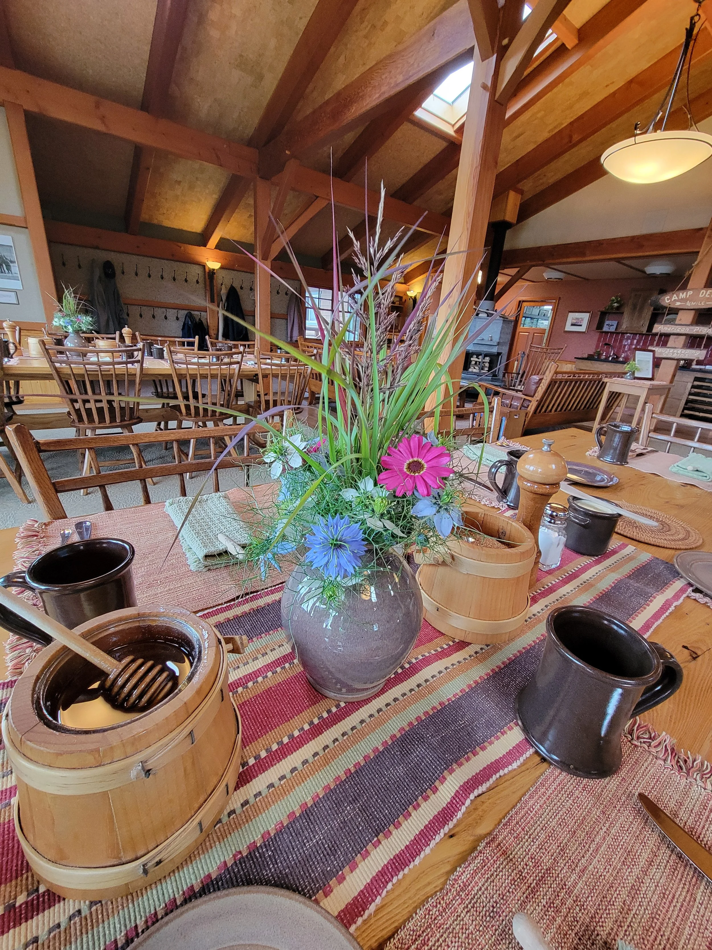 Dining area at Camp Denali with fresh flowers on the table and large wooden beams throughout the lodge.