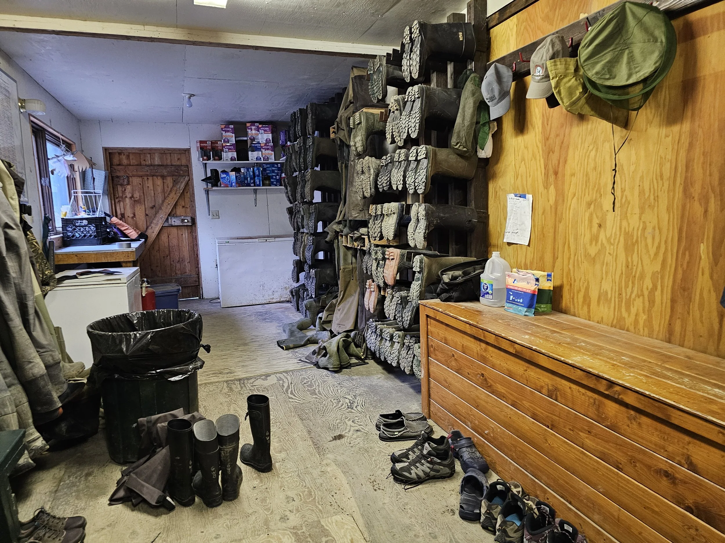 Rubber boots and waders lined up on a cabin deck at Silver Salmon Creek Lodge for guest use