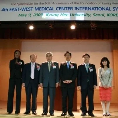 Six individuals standing on a stage in formal attire, with a banner above them that commemorates the 40th anniversary of Kyung Hee Medical Center International Symposium, held on May 9, 2009, at Kyung Hee University in Seoul, South Korea.