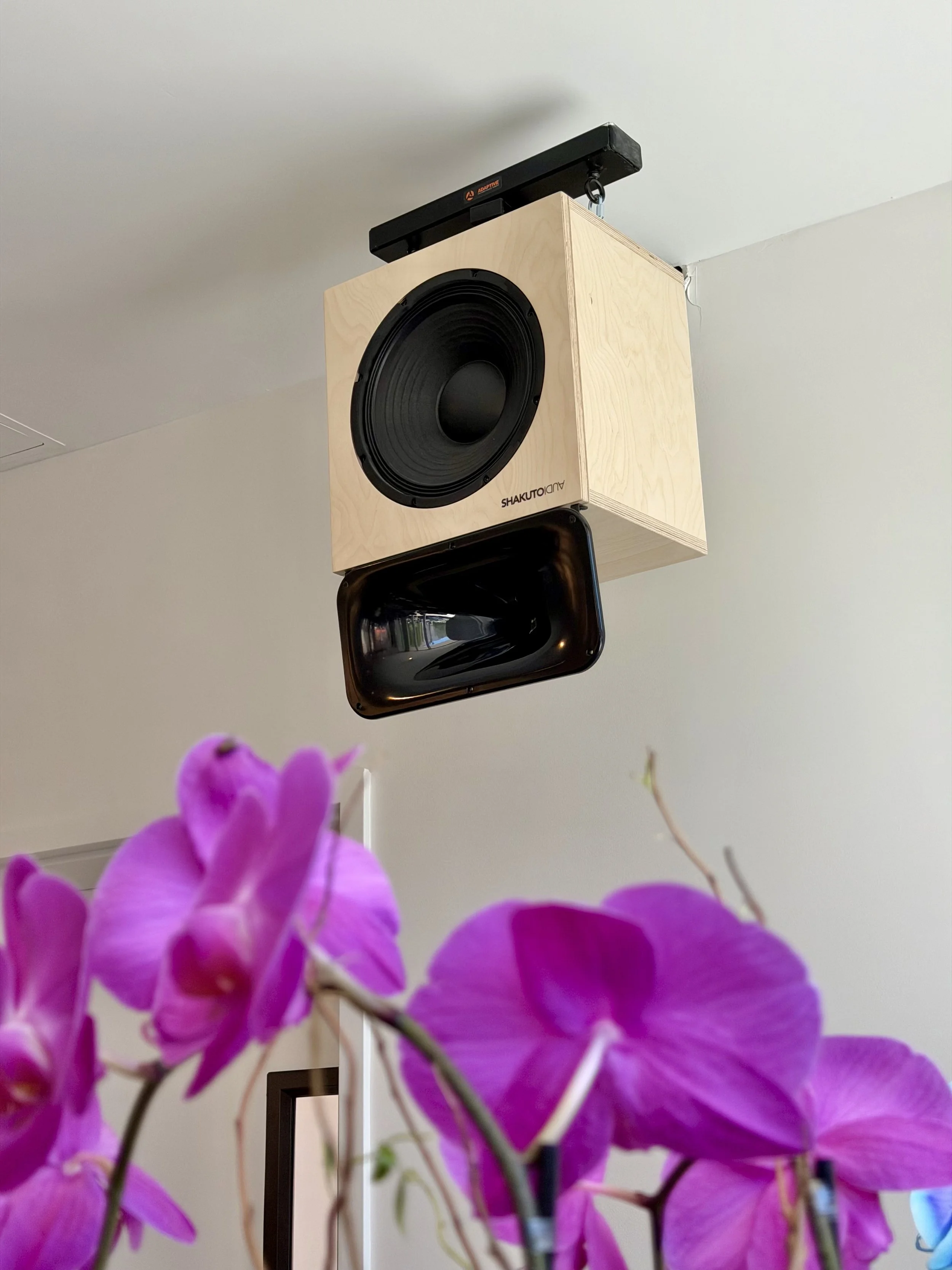 A vintage speaker with a wood cabinet and a black speaker cone, featuring a silver, textured horn overlay on top. altec 811b horns