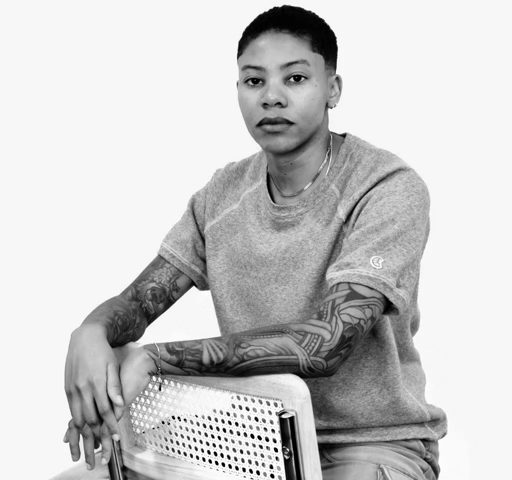 black and white photo of Julia sitting on one of her barstools, from the side this time